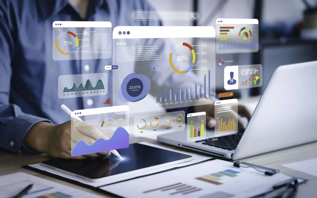 Person using a tablet and laptop surrounded by charts and virtual data dashboards, illustrating personal branding