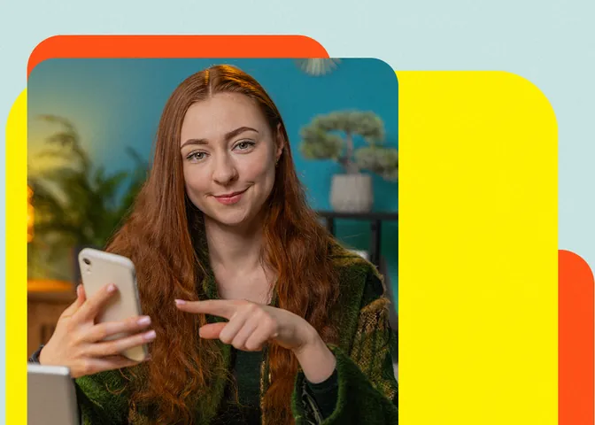 Mulher ruiva sorridente aponta para o celular na mão, sugerindo um link na bio que vende, sobre fundo amarelo e laranja