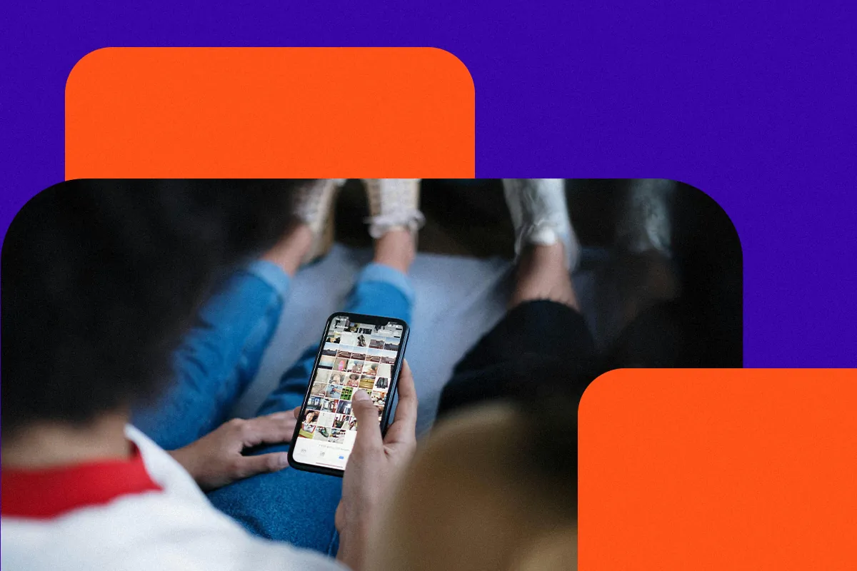 Person holding a phone showing a photo grid on the screen, like a digital storefront, next to friends sitting nearby