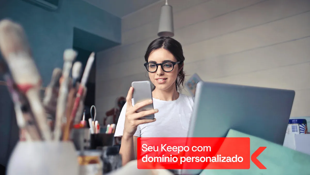 Woman with glasses smiles while using her phone in front of a laptop, with a red banner about Keepo with a custom domain