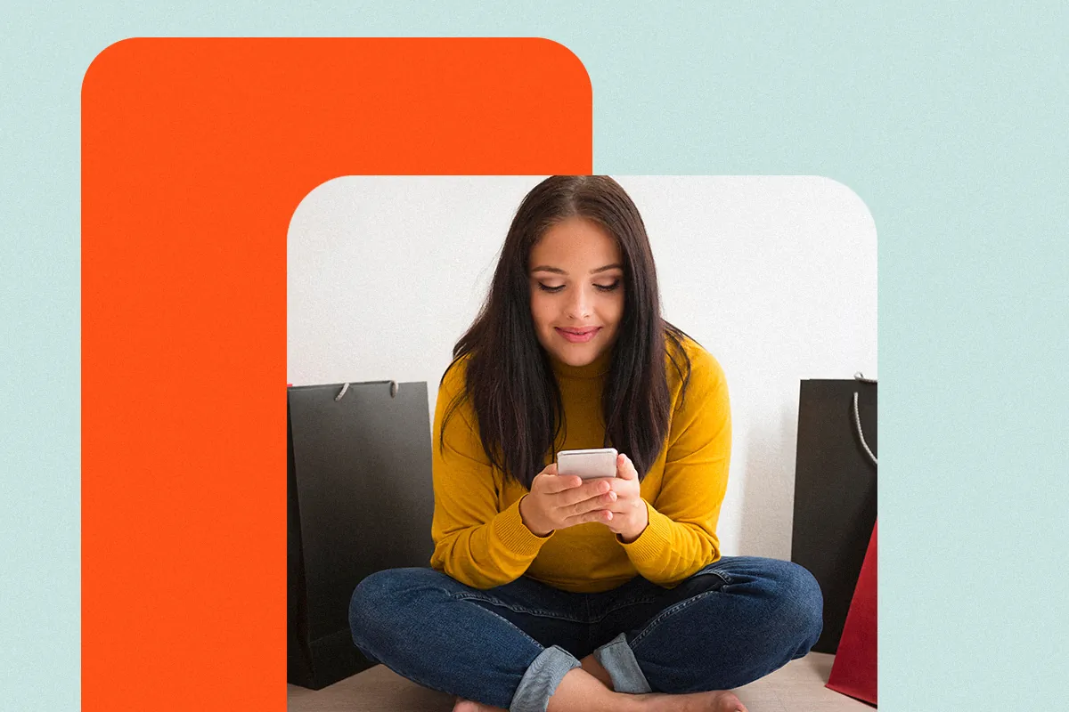 Woman sitting on the floor among shopping bags using her phone, suggesting a conversion journey through a link in bio