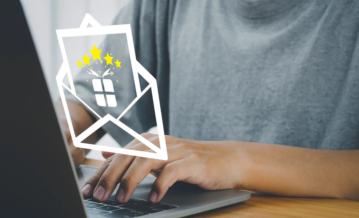 Person typing on a laptop with icons of an open envelope, a gift and stars, representing building customer loyalty through email