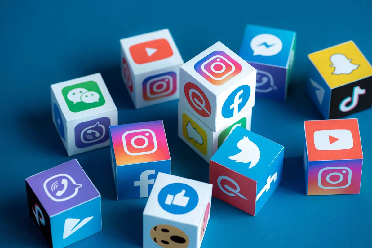 Paper cubes with social media icons scattered on a blue background, symbolizing digital presence and personal branding