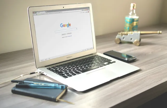 Open laptop showing a Google search page on a wooden table with a phone and notebook, local SEO theme